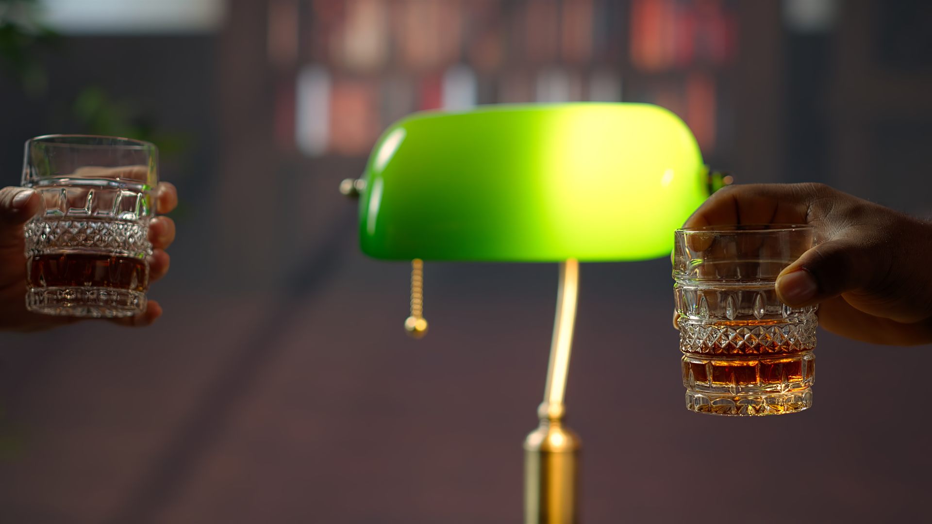 Klassische Bibliothek mit grüner Leselampe, Holzregalen und zwei Whiskygläsern